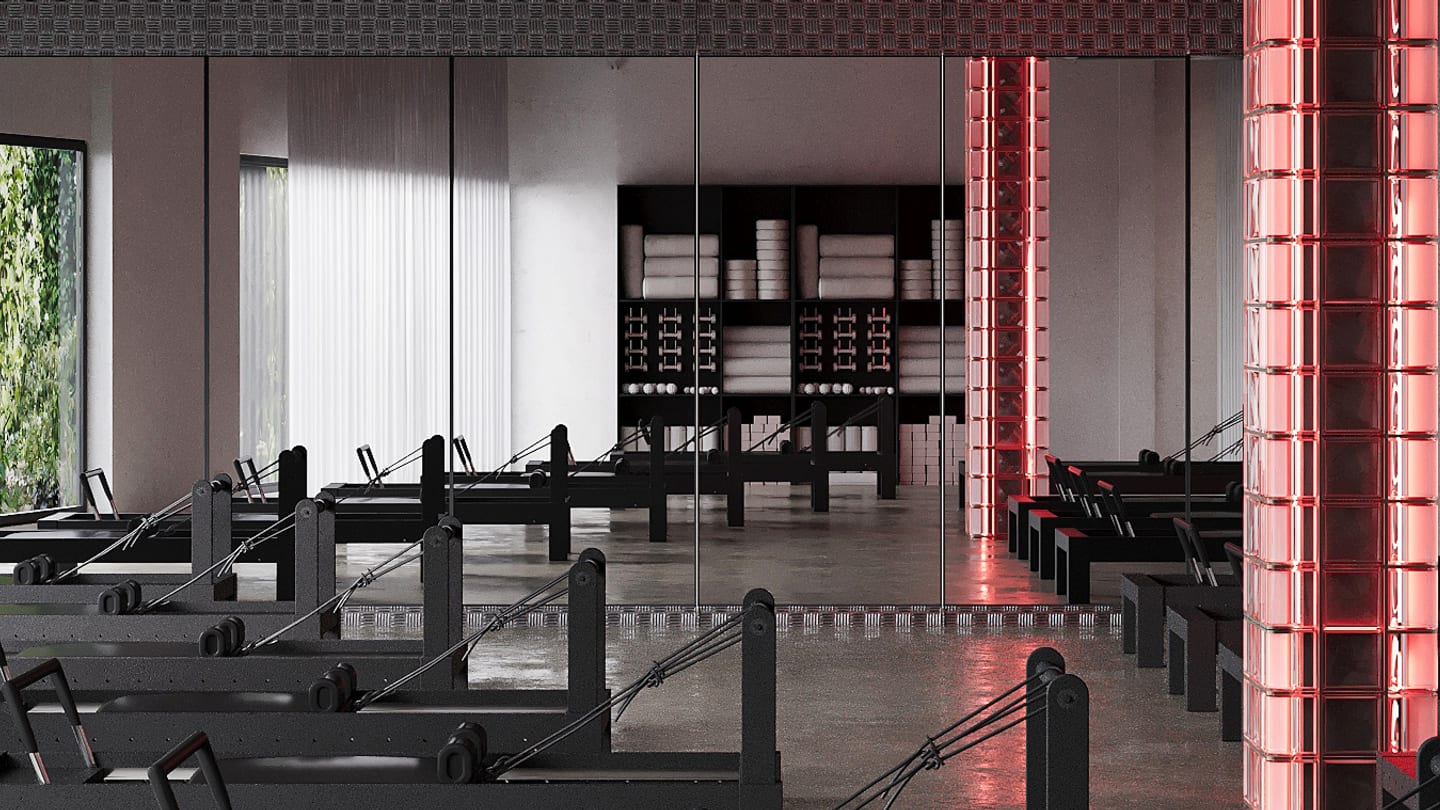 Le studio Reformer de Studio MA, reformers noirs alignés et colonnes de briques de verre éclairées en rouge.